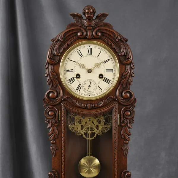 An ornate, classic vintage wall clock made of dark wood with brass accents and decorative carvings.