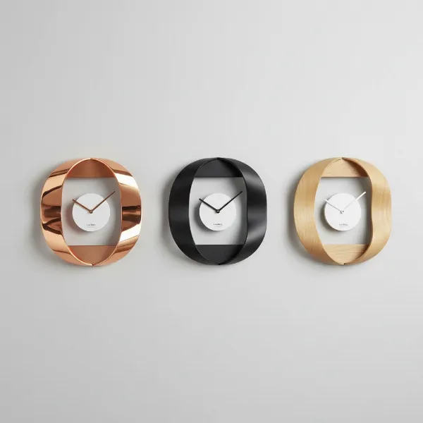Collection of Umbra Ribbon clocks in different finishes: copper, black steel, and natural beech wood.
